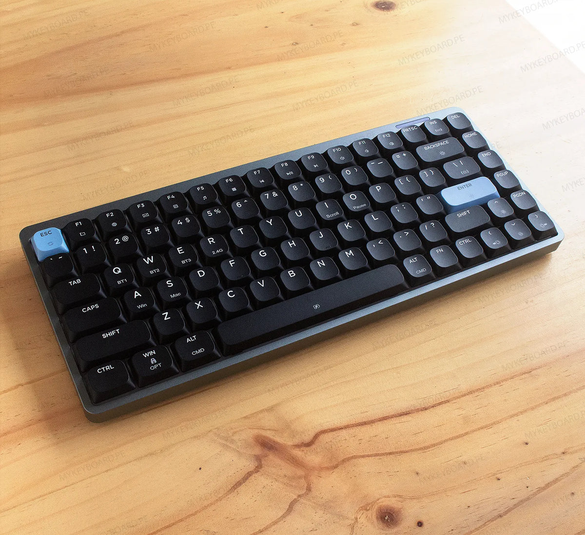 Teclado mecánico Epomaker Luma84 en formato 75% con chasis gris, teclas negras y acentos celestes en fondo de madera.