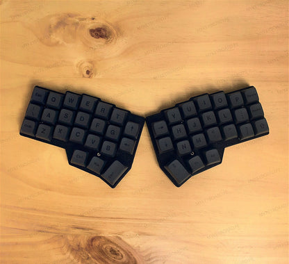 Teclado mecánico ergonómico dividido MyKeyboard Corne V4.1 con teclas negras sobre superficie de madera clara