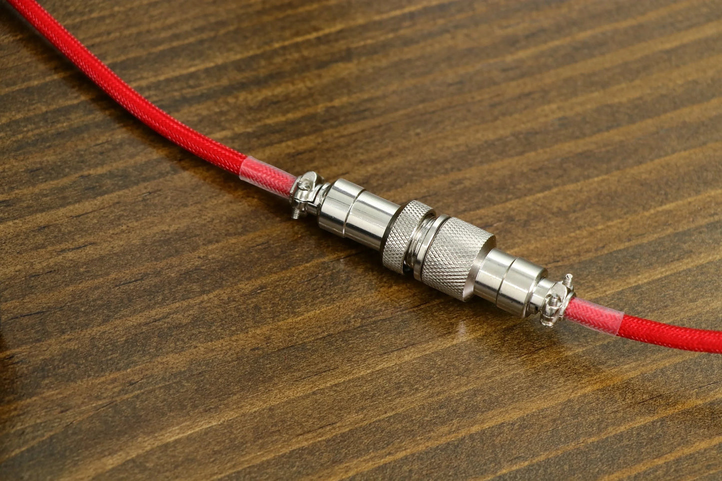 Cable enrollado MyKeyboard EPOMAKER rojo con conector aviador de metal sobre superficie de madera