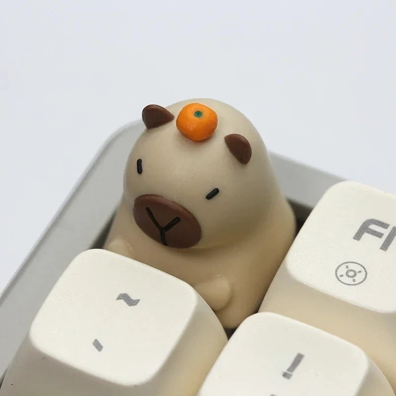 Keycap artesanal MyKeyboard con forma de capibara beige con una pequeña naranja en la cabeza para switches MX