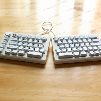 Teclado mecanico dividido MyKeyboard ZUOYA GMK70 blanco formato 65% con perilla de volumen sobre mesa de madera