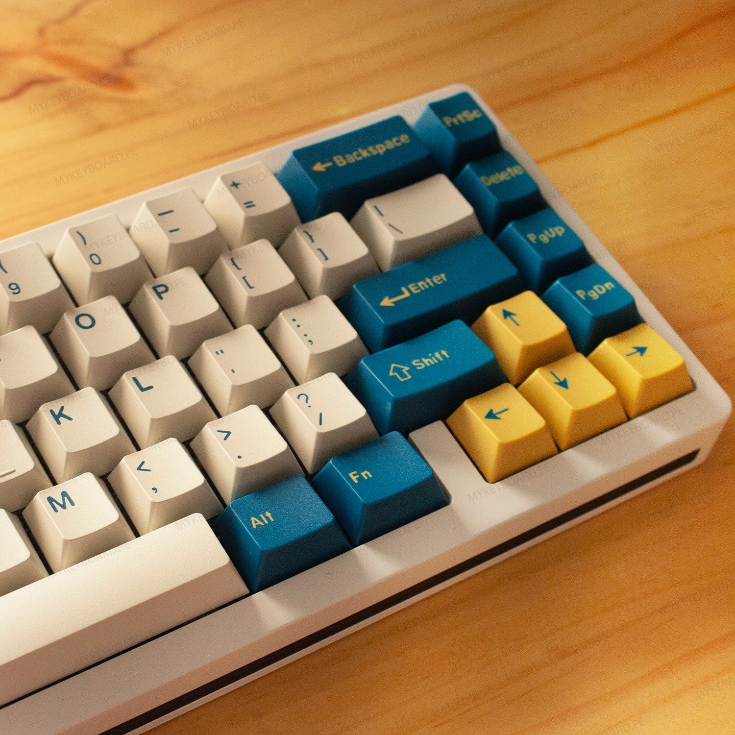 Teclado mecánico MyKeyboard Weikav NUT65 Merlin 65% con teclas PBT en tonos blanco, azul y amarillo sobre madera.