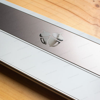 Detalle de la carcasa blanca y gris del teclado MyKeyboard Weikav NUT65 Merlin con logo de bellotas metálico