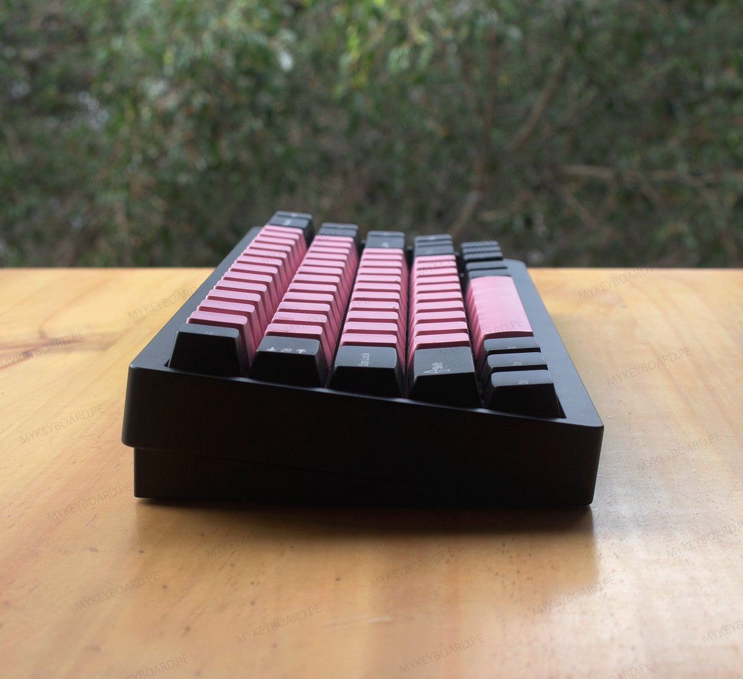 Teclado mecánico MyKeyboard Weikav NUT65 65% con teclas rosas y negras sobre una mesa de madera